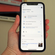 A photo of a person holding an iPhone up with the Google Search app opened to the Search history settings